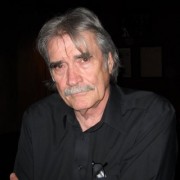 Older man with gray hair and mustache and a serious expression